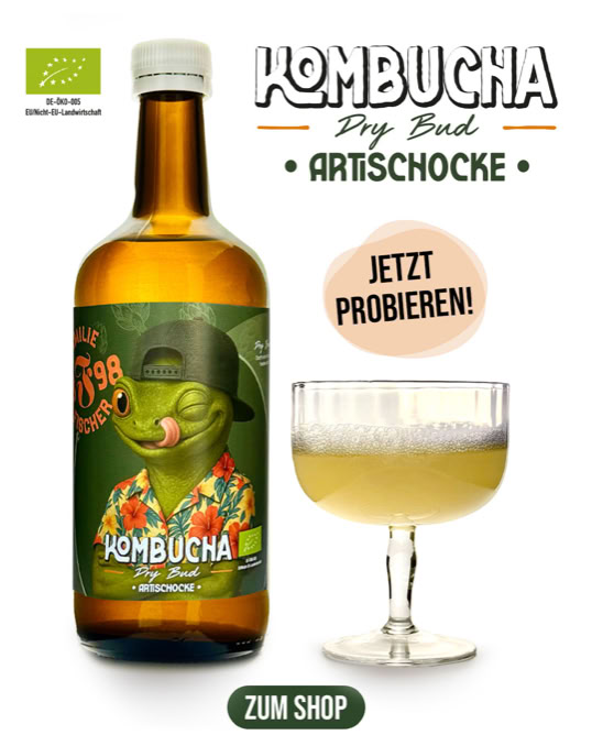 Eine Flasche Kombucha mit einem Etikett, das eine anthropomorphe Echse mit Hut und Hawaiihemd zeigt, daneben ein Glas mit einem Getränk. Text: "Kombucha Dry Basil Artischocke" und "Jetzt probieren!".