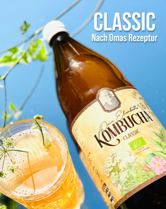 Eine Flasche Kombucha Classic von Familie Fischer 1898 mit einem gefüllten Glas